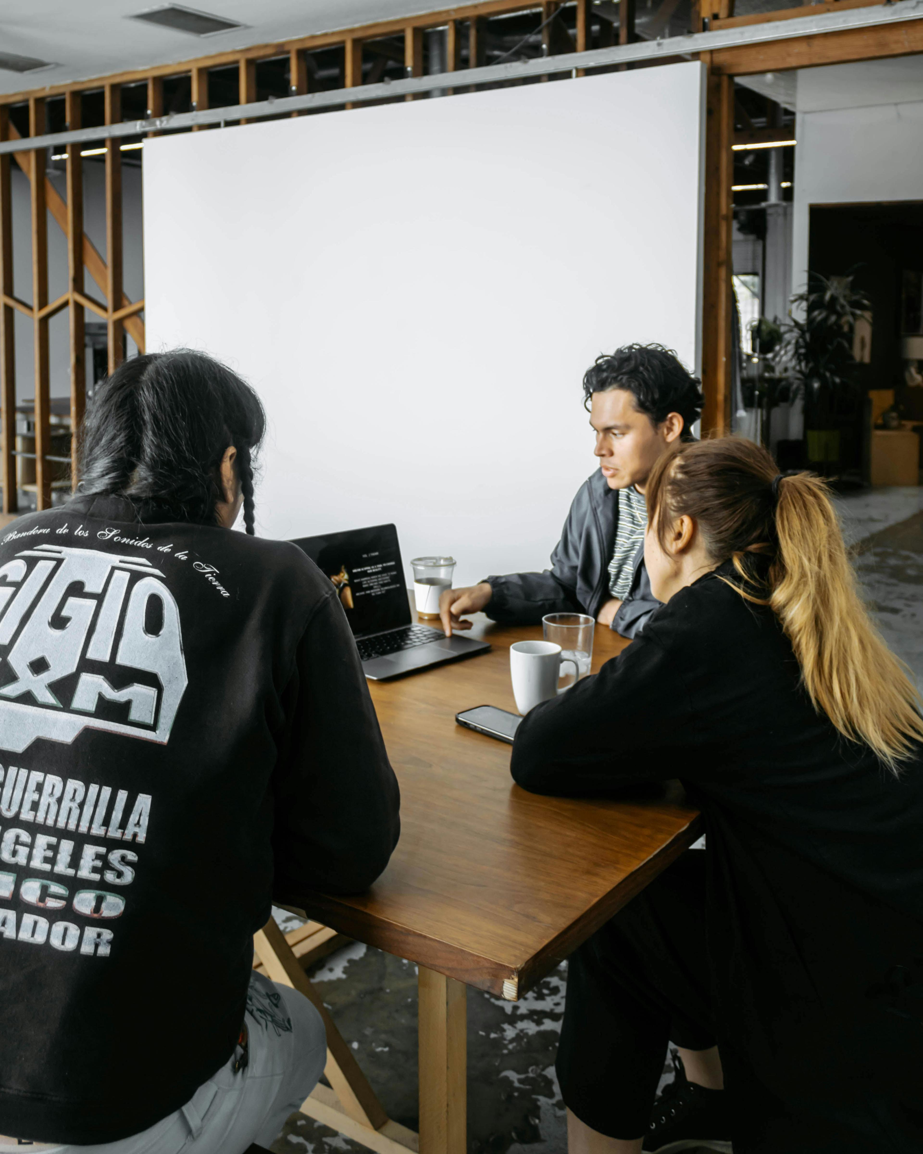 Photographer showing clients a deck of final product images on a laptop, with one client pointing at the screen and the other client looking closely at the images.