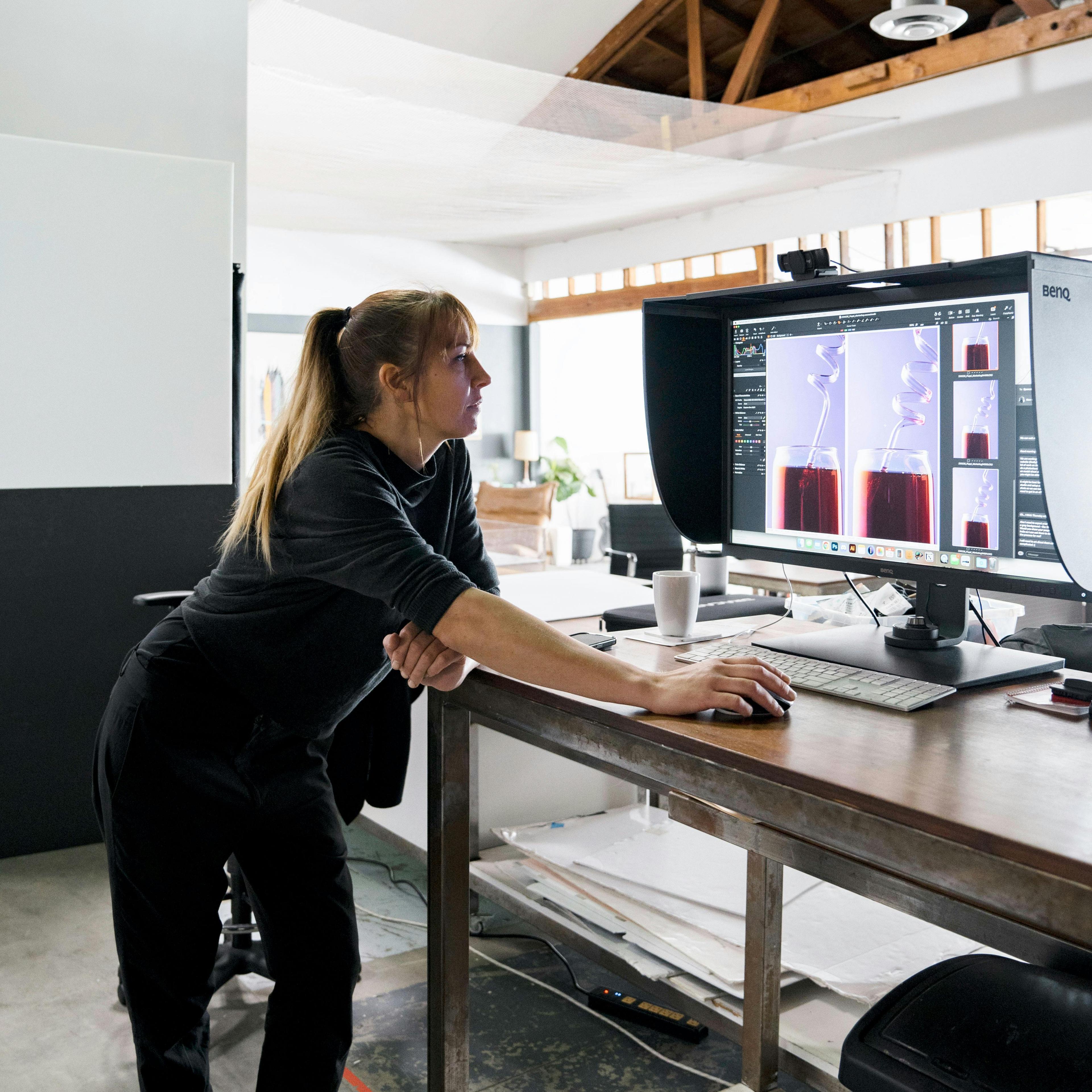 Photographer holding up a picture of a Poppi beverage to a client for final approval. The client is seated across from the photographer, looking at the image on a computer screen while the photographer points to specific details on the print